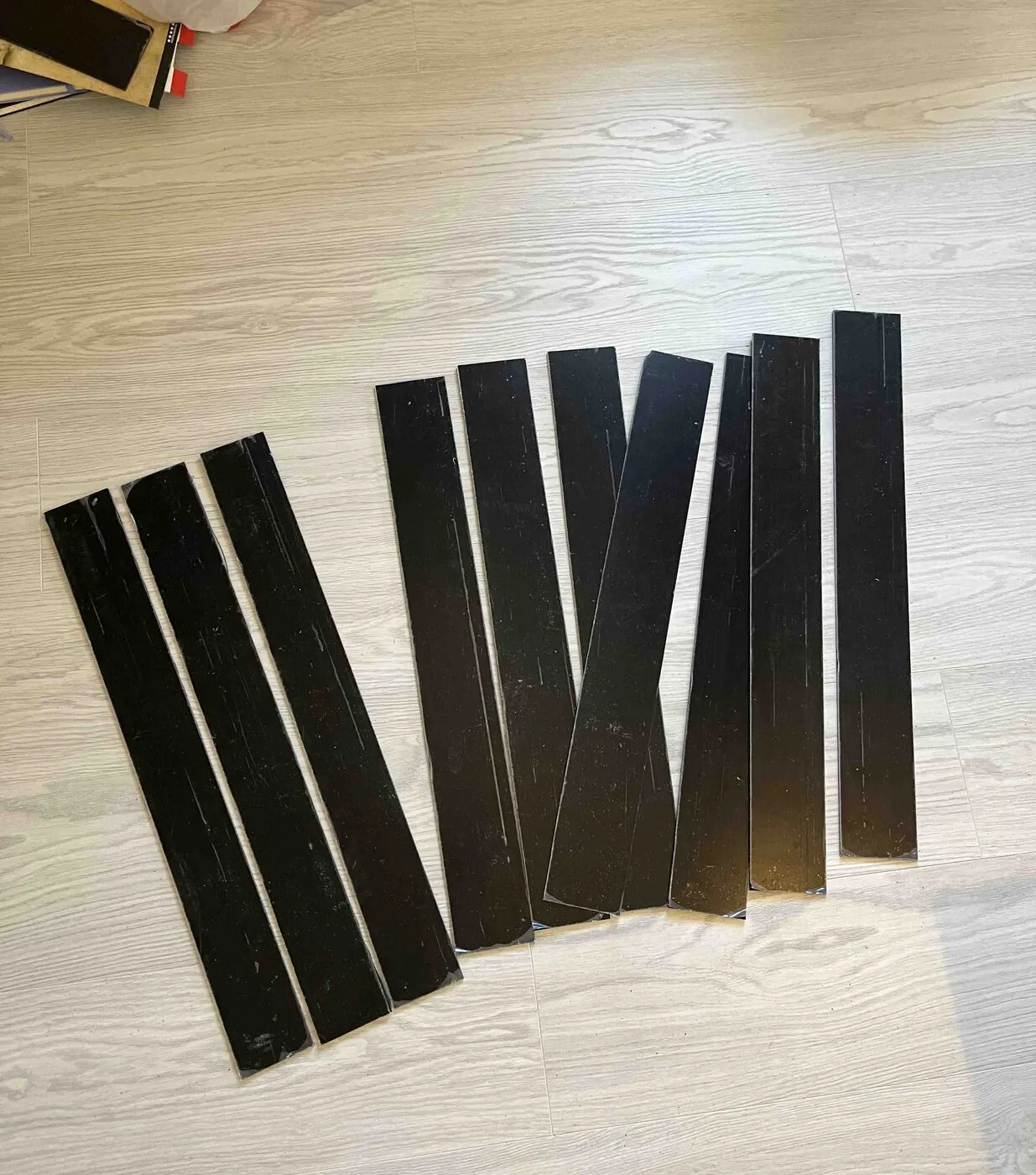Strips of black acrylic laid out on a wooden floor, cut to size for the planters.